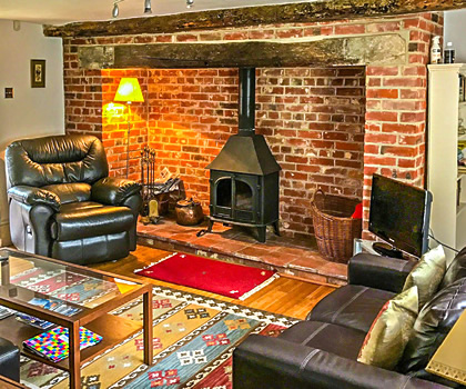 Interior photo of Church Cottage showing the living room fireplace & wood burner